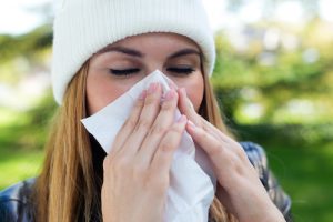 Outdoor portrait of beautiful girl with tissue having flu or allergy.